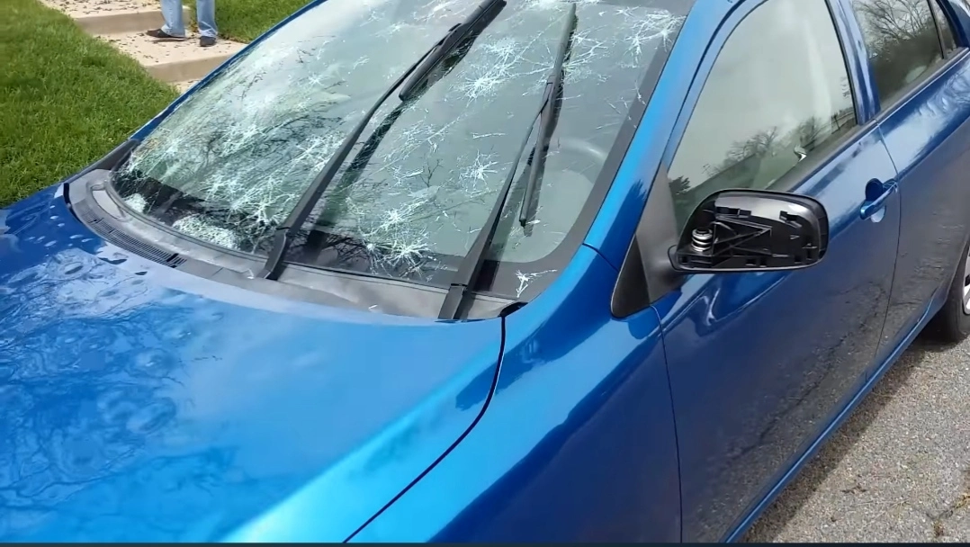 Blue sedan in Austin with a windshield cracked by spring hail damage